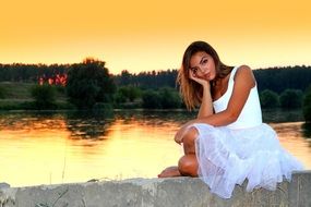 girl in a white dress near the lake at sunset