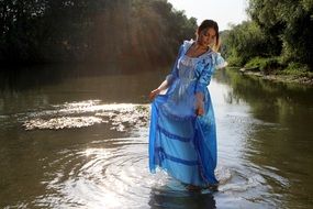 girl in a long blue dress posing on the lake