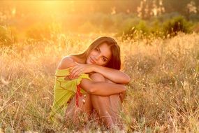 beautiful girl sitting on the grass in the sunset