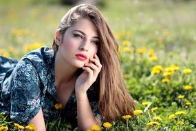 beautiful long haired caucasian Girl lays on meadow among Dandelions