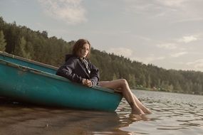 girl is sitting in a green boat on the lake