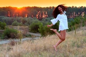brunette in white in a jump at sunset