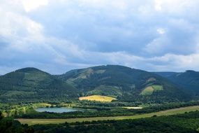 scenic green summer Landscape with lake in front of mountains on cloudy weather