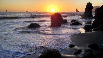 boulders on the ocean at sunset