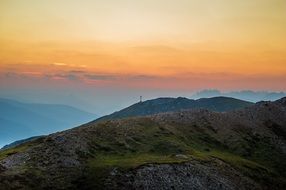 Cross on a beautiful mountain top at colorful, gradient sunrise background