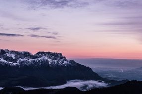 pink sunset over mountains and foggy shore