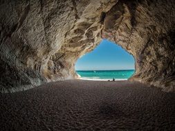 rock arch on the beach with water on horizon in italy