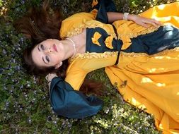 girl lies in a long yellow dress