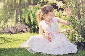 little girl in a light beautiful dress in a sunny garden