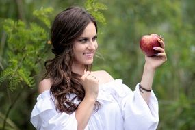 woman looking at the apple in her hands close-up on blurred background