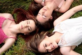 three beautiful girls with long hair in a summer meadow