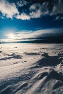 Snowy landscape beneath blue sky at sunset