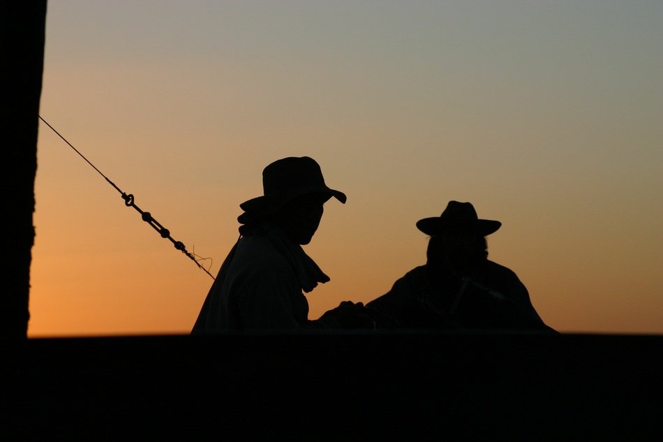 silhouettes of fishermen at sunset