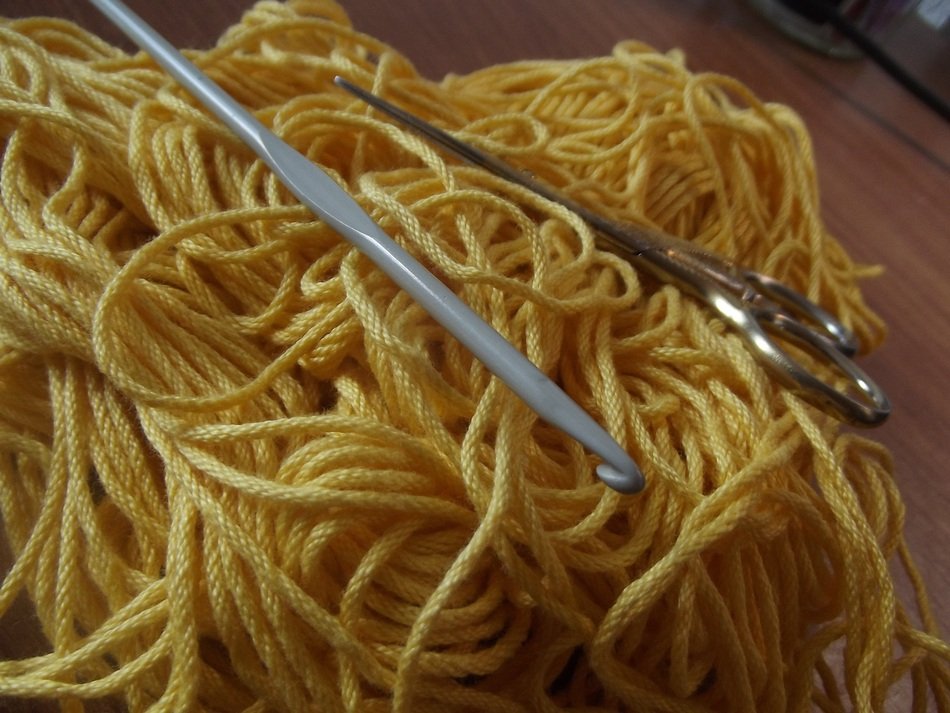 hook with scissors lie on yellow yarn