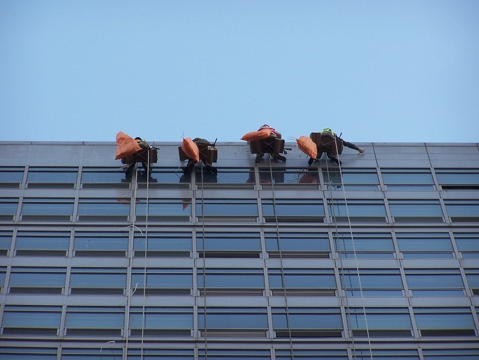 workers wash windows on the facade of the building
