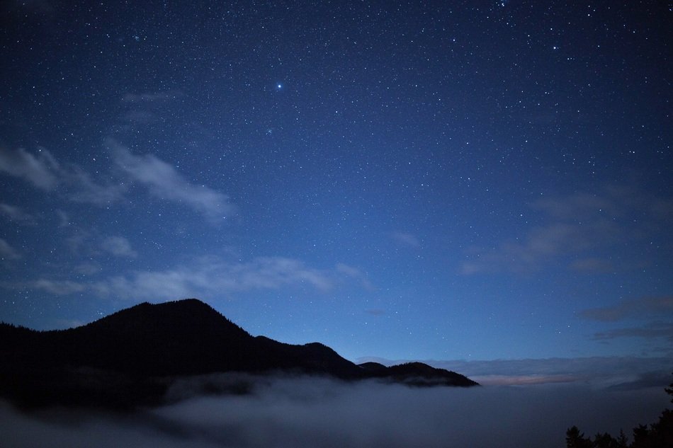 stars in the sky above the top of the mountain at night
