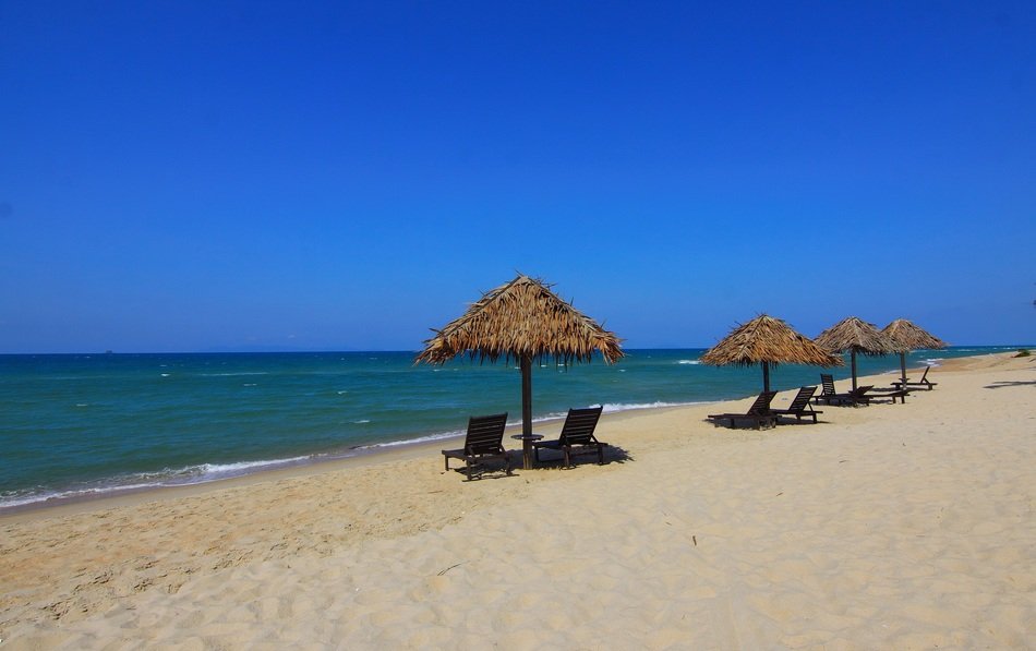 chairs under umbrellas on the beach near the water