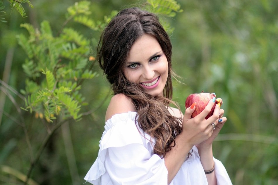 girl in a white dress with an apple in her hands