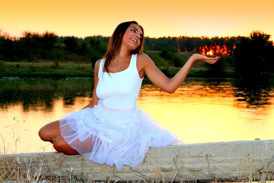 photo of happy girl on the lake in the rays of sunset