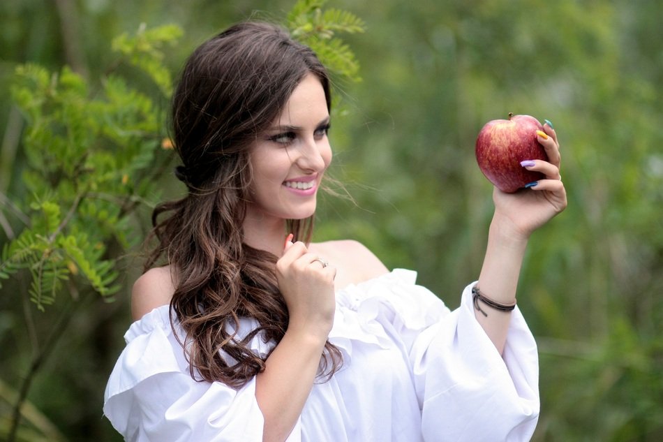 woman looking at the apple in her hands close-up on blurred background