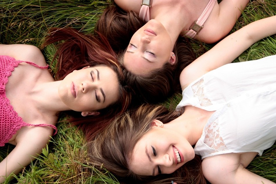 three beautiful girls with long hair in a summer meadow