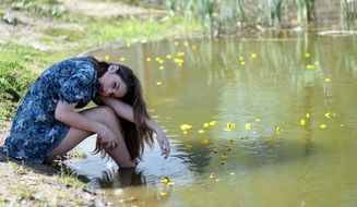 girl with long hair sitting on the riverbank