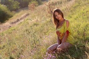 seductive brown-eyed girl on the grass among the colorful plants