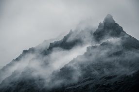 black and white photo of fog over a mountain range