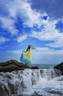 girl in a spring dress on a rocky seashore