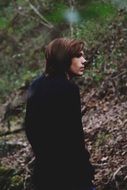 young man in a black cloak on a background of a slope