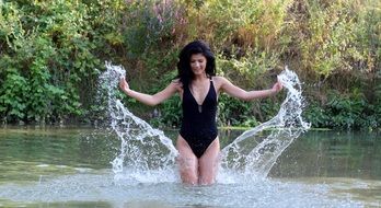 girl in a black bathing suit in spray of water