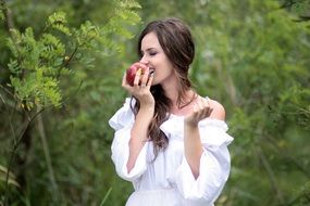 smiling young woman with an apple in the forest