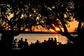 Group of people on a lake bank at the sunset