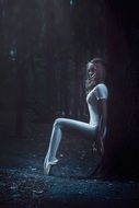 ballerina stands near a tree in the forest as a fantasy