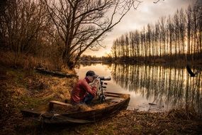 Wildlife photographer in boat on the beautiful and colorful riverside at fall evening