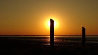 pillars on the shore of the North Sea against the backdrop of a golden sunset