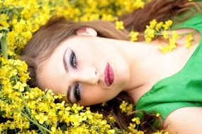 beautiful woman laying on the yellow flowers close-up on blurred background