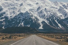 Highway receding into the rocky snowy mountains