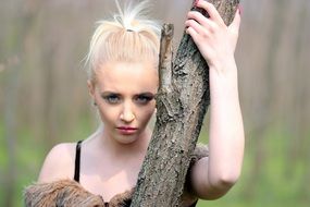 photo of a blonde at a tree trunk