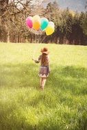 girl with colorful balloons in the forest