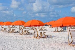 orange umbrellas over sun loungers on a sandy beach