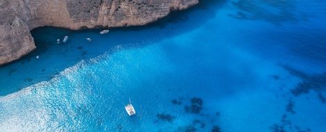 Boats on Turquoise Sea near rocky Coast