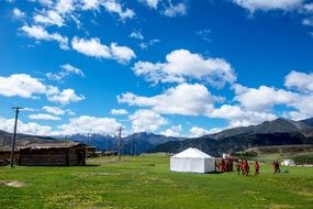 Beautiful village on the green field at blue sky with white clouds on landscape in Tibet