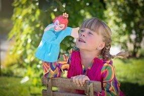 blonde girl with a doll among nature