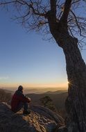 person sits on mountain summit loking at scenic landscape, usa, virginia, shenandoah national park
