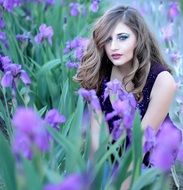 Girl in the iris flowers on the meadow