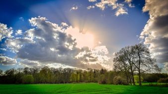 sun in the clouds over the meadow