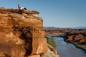 man on a cliff near a green river