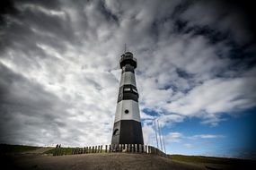 fenced black striped lighthouse on Beach, Netherlands