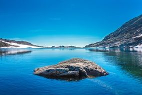 rocky formation in the middle of a mountain lake